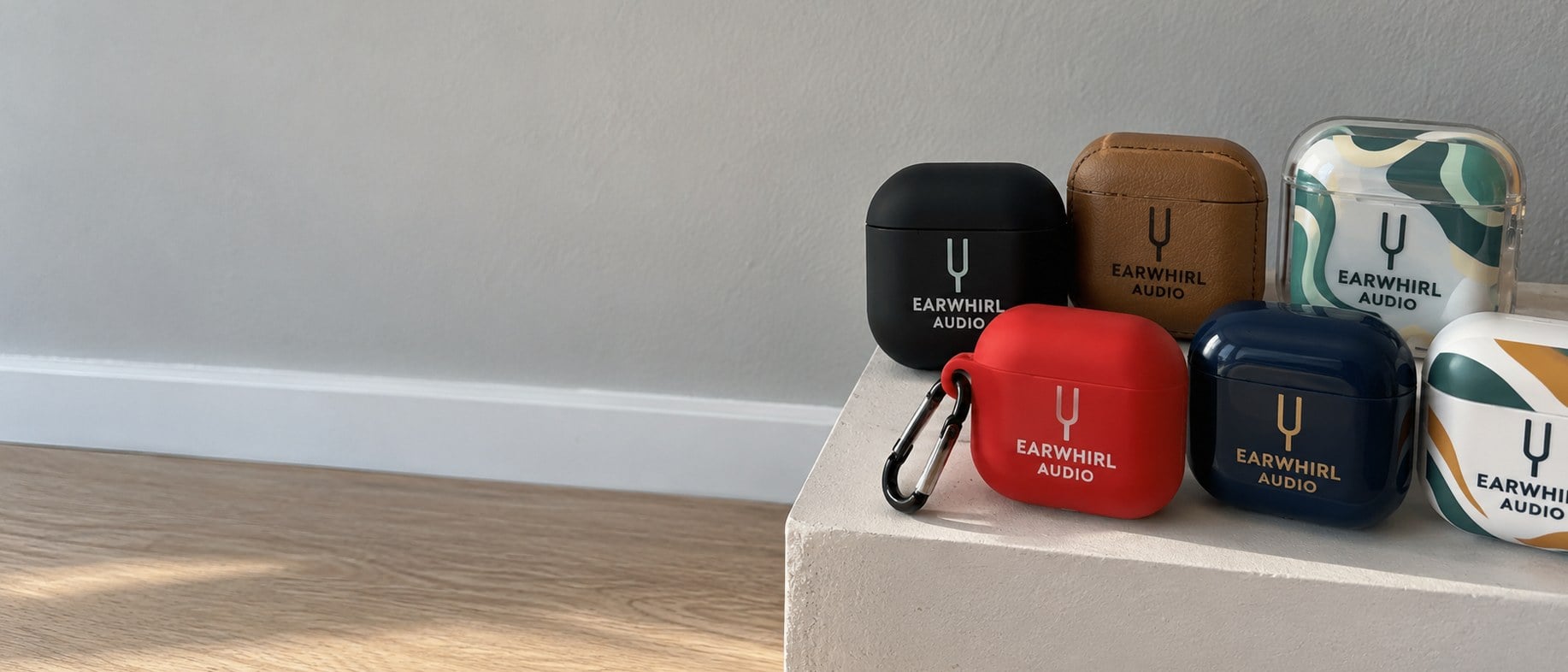 Custom silicone, leather, clear, keychain and hard-shell earbud cases with logos grouped on a small white plinth